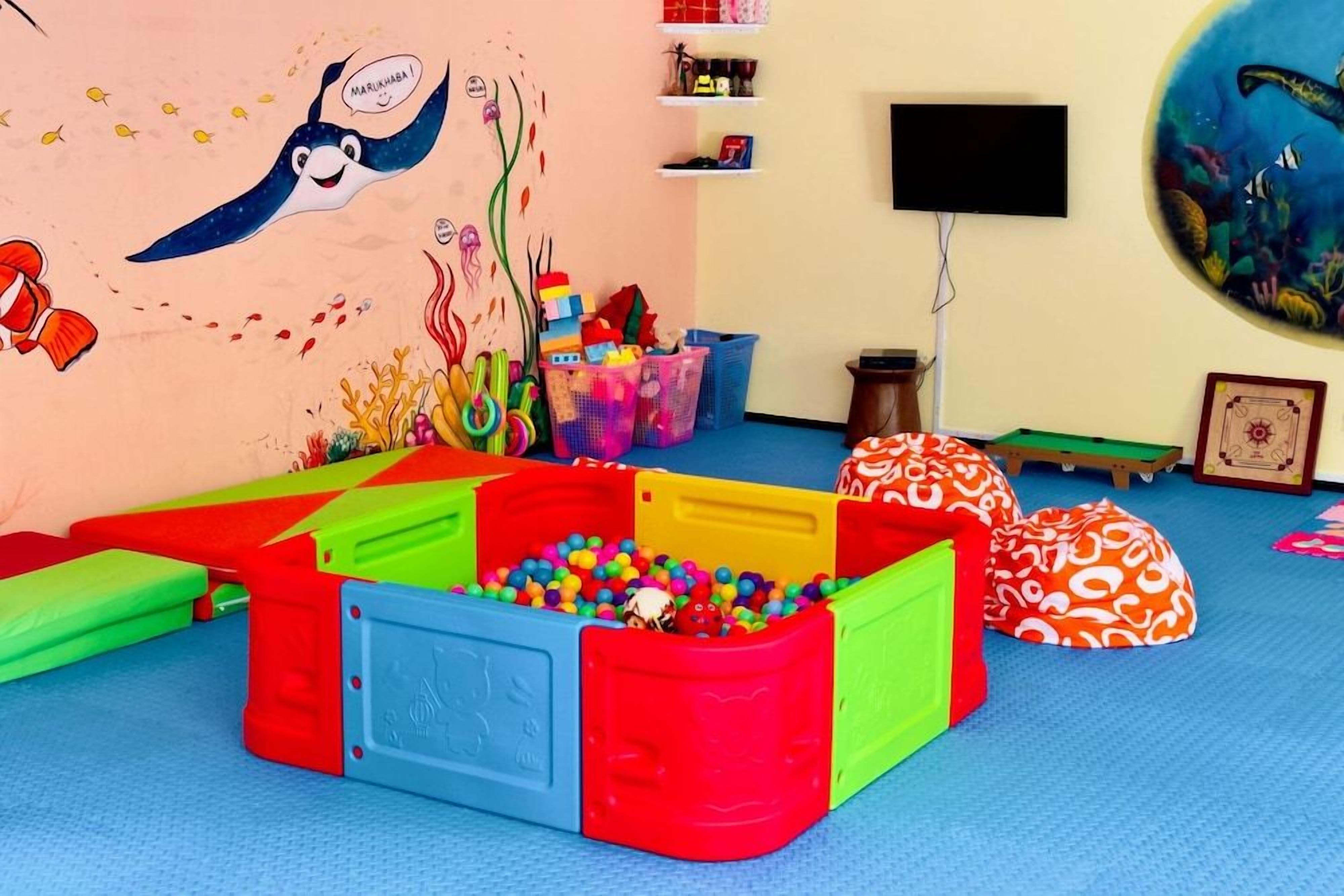 Zona de juegos con estructuras coloridas y un mural.