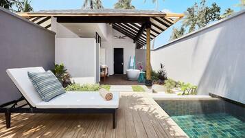 A modern outdoor lounge area with a pool, a sunbed, and a covered walkway.