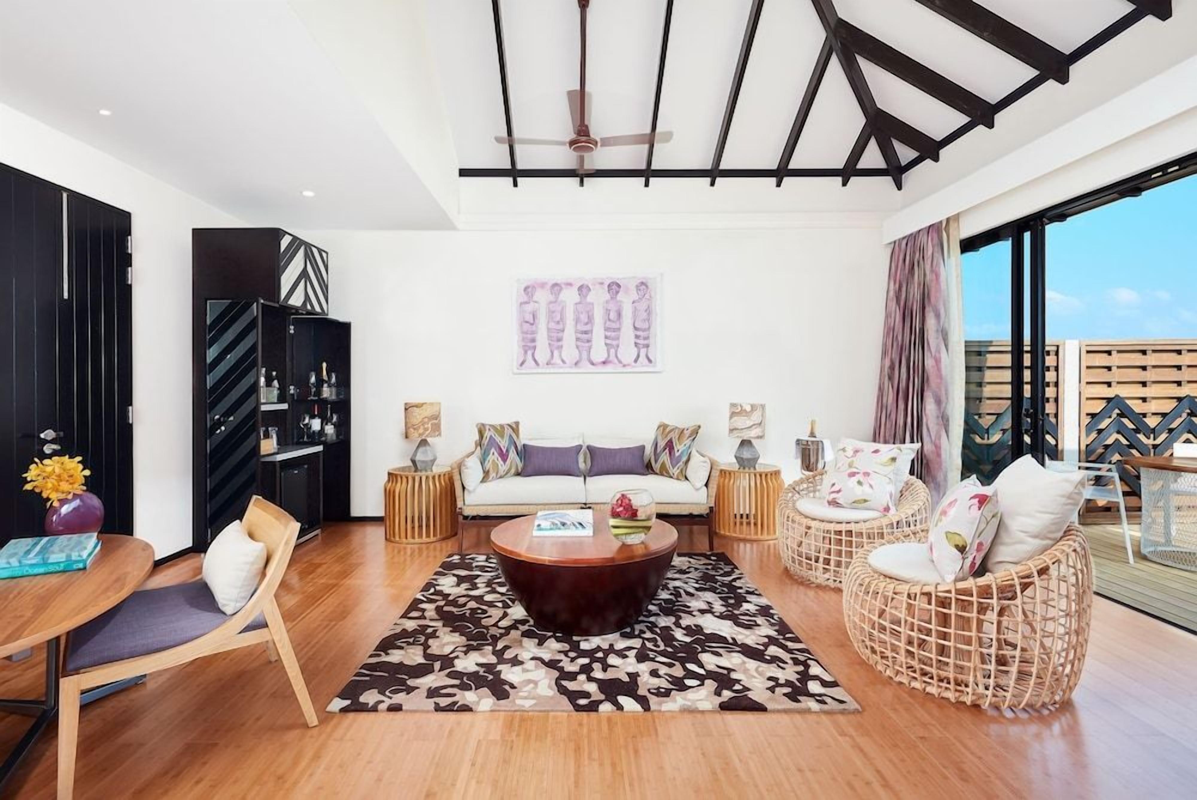 A modern living room with a sofa set, a coffee table, and wicker chairs.