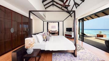 Quarto com cama, televisão e vista para o oceano.