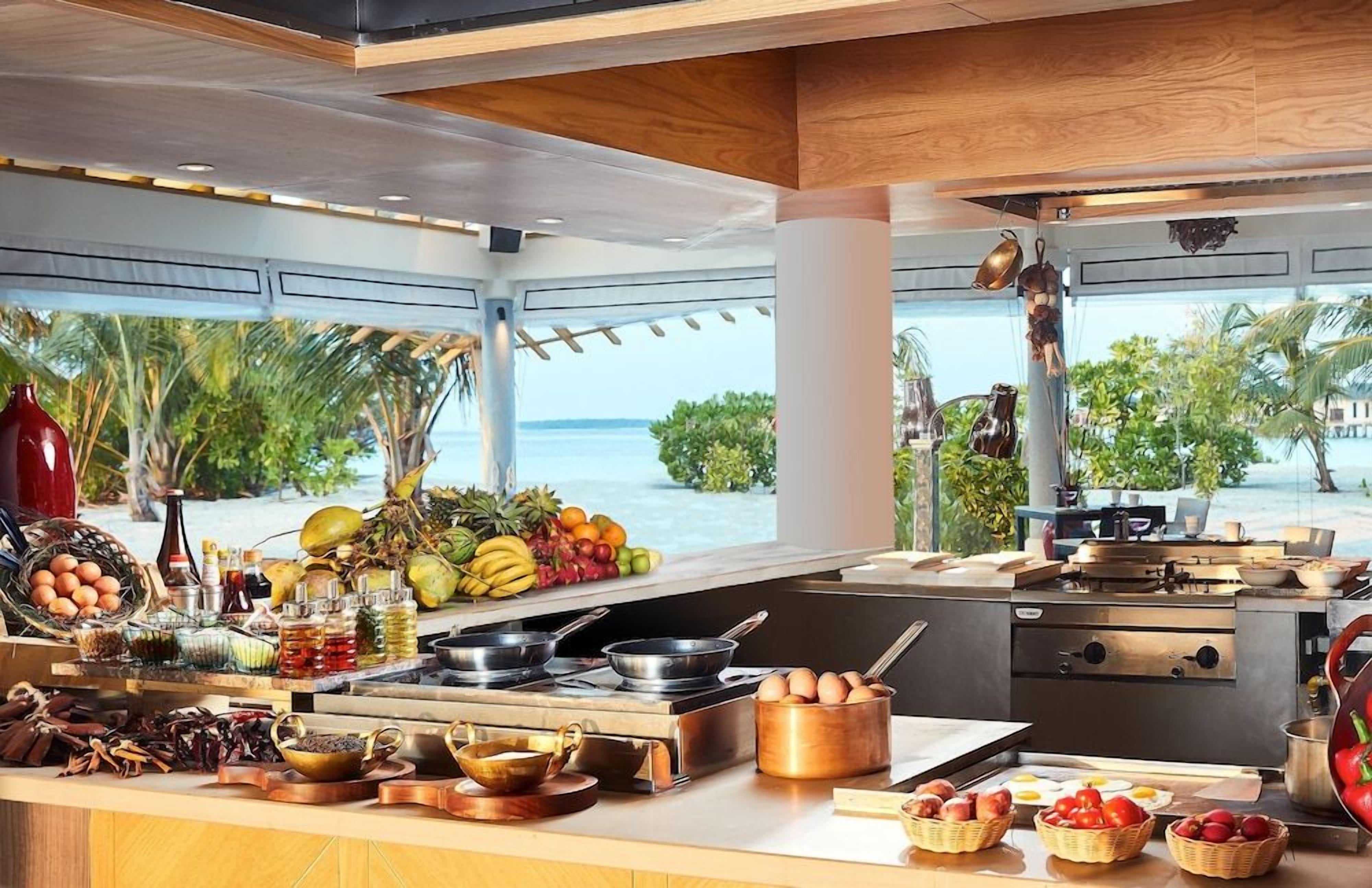 A kitchen with a view of the ocean, equipped with modern appliances and a variety of fresh produce.
