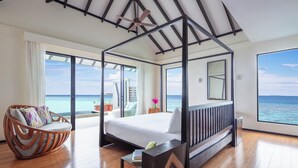 Une chambre avec un grand lit, un plafond en bois et une vue sur l’océan.