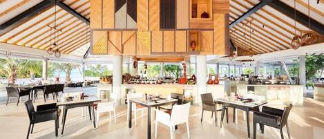 A spacious dining area with multiple tables and chairs, a bar area, and a view of the outdoors.