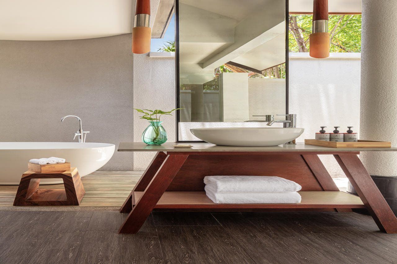 Une salle de bain moderne avec une baignoire sur pieds, un grand miroir et un meuble-lavabo en bois.
