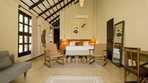A hotel room with a bed, two chairs, a sofa, a large mirror, and a ceiling with exposed beams. - Selina Tulum (Tulum)