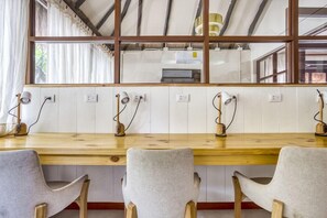 A long wooden table with four chairs, a window with curtains, and a kitchen area in the background. - Selina Tulum (Tulum)