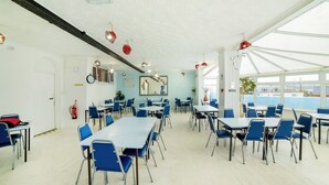 A spacious room with tables and chairs, a fire extinguisher, and a large window. - OYO Marina (Sandown)