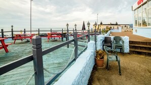 A coastal pier with a wooden walkway, picnic tables, and chairs. - OYO Marina (Sandown)