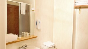 Un baño con lavamanos, espejo, toallero y retrete.