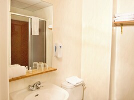 Un baño con lavamanos, espejo, toallero y retrete.