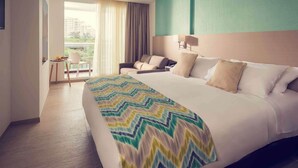 A hotel room with a large bed, a seating area with a chair and table, and a view through a window. - Mercure Santa Marta Emile (Santa Marta)