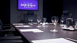 A conference room at Mercure Hotels with a long table set for meetings, chairs, and a television displaying the hotel name. - Mercure Santa Marta Emile (Santa Marta)