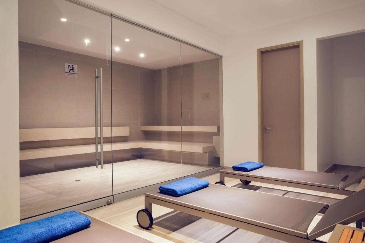 A modern room with a glass partition, a wooden floor, and a blue towel on a massage table.