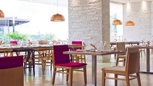 A restaurant with wooden tables and chairs, stone walls, and hanging pendant lights. - Mercure Santa Marta Emile (Santa Marta)
