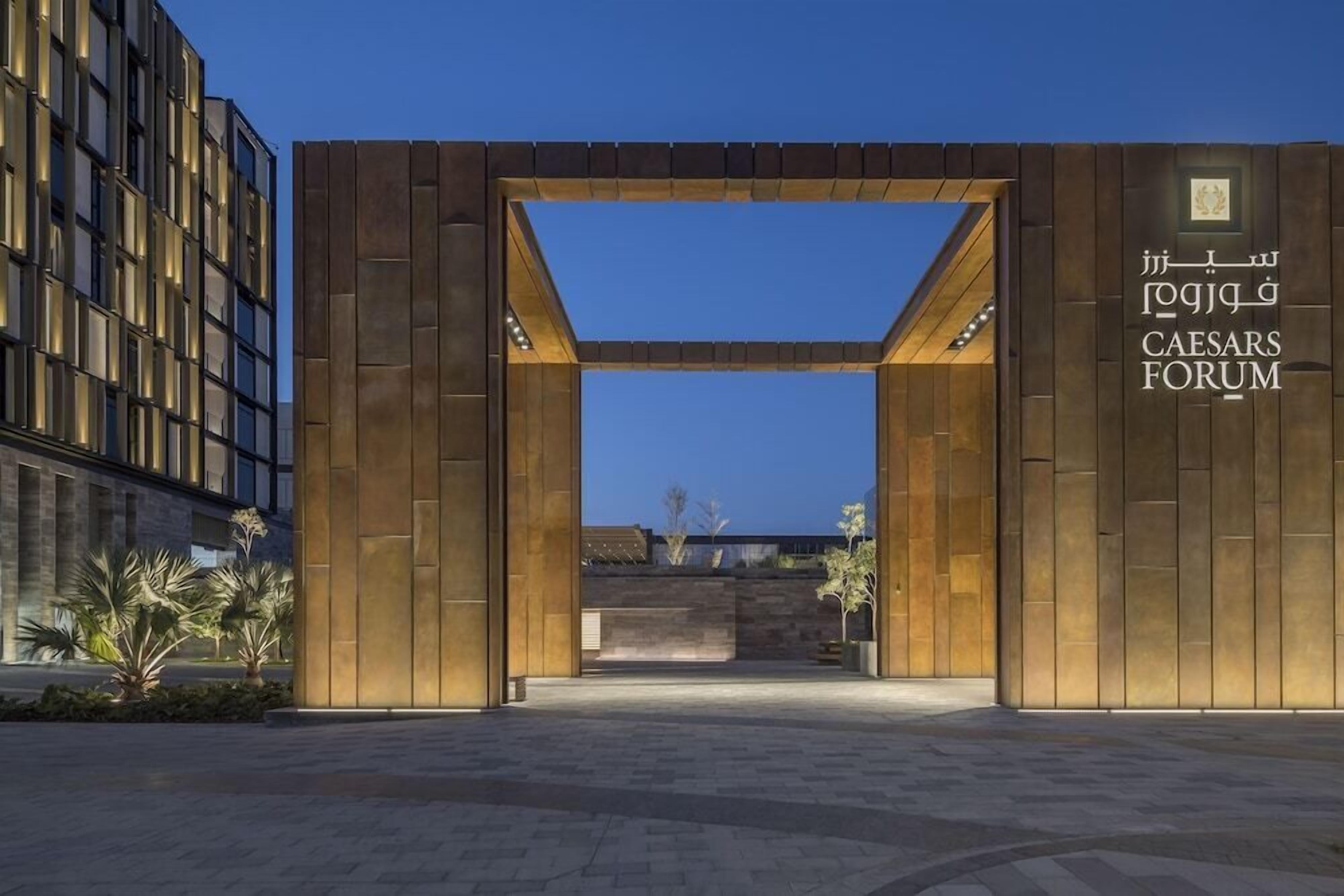 Une entrée moderne avec une arche en bois et une enseigne indiquant « Caesars Forum ».