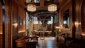 Un vestíbul amb sofàs de pell, zona de bar i lluminàries.
