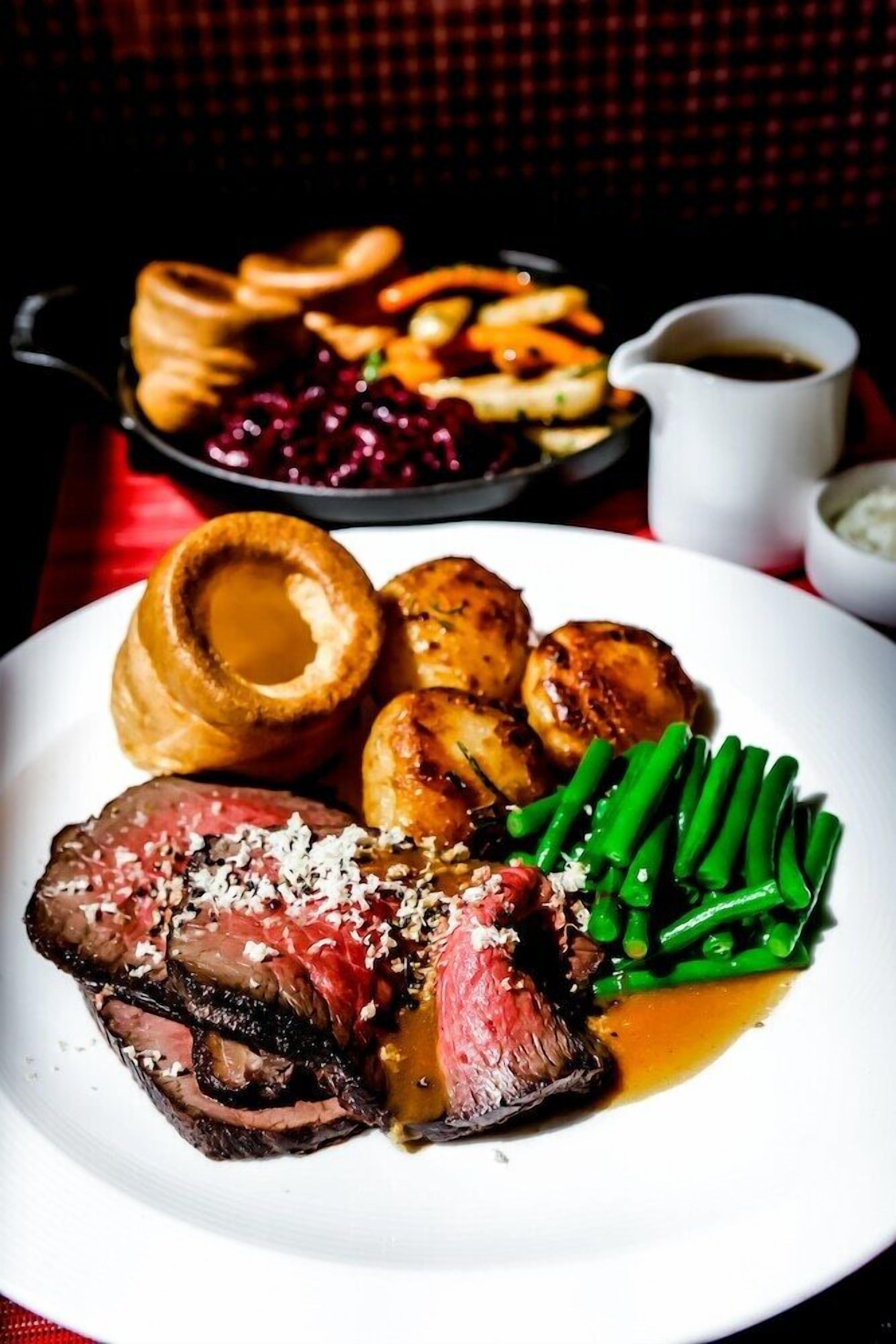 Een bord eten met vlees, Yorkshire pudding en groene bonen.