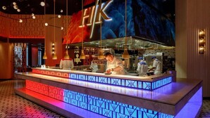 Un taulell de restaurant amb un disseny modern, il·luminat per llums penjants i un rètol de neó.