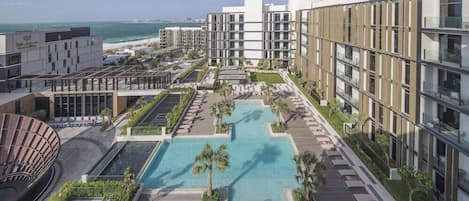 A modern hotel with a rooftop pool, multiple buildings, and a view of the ocean.
