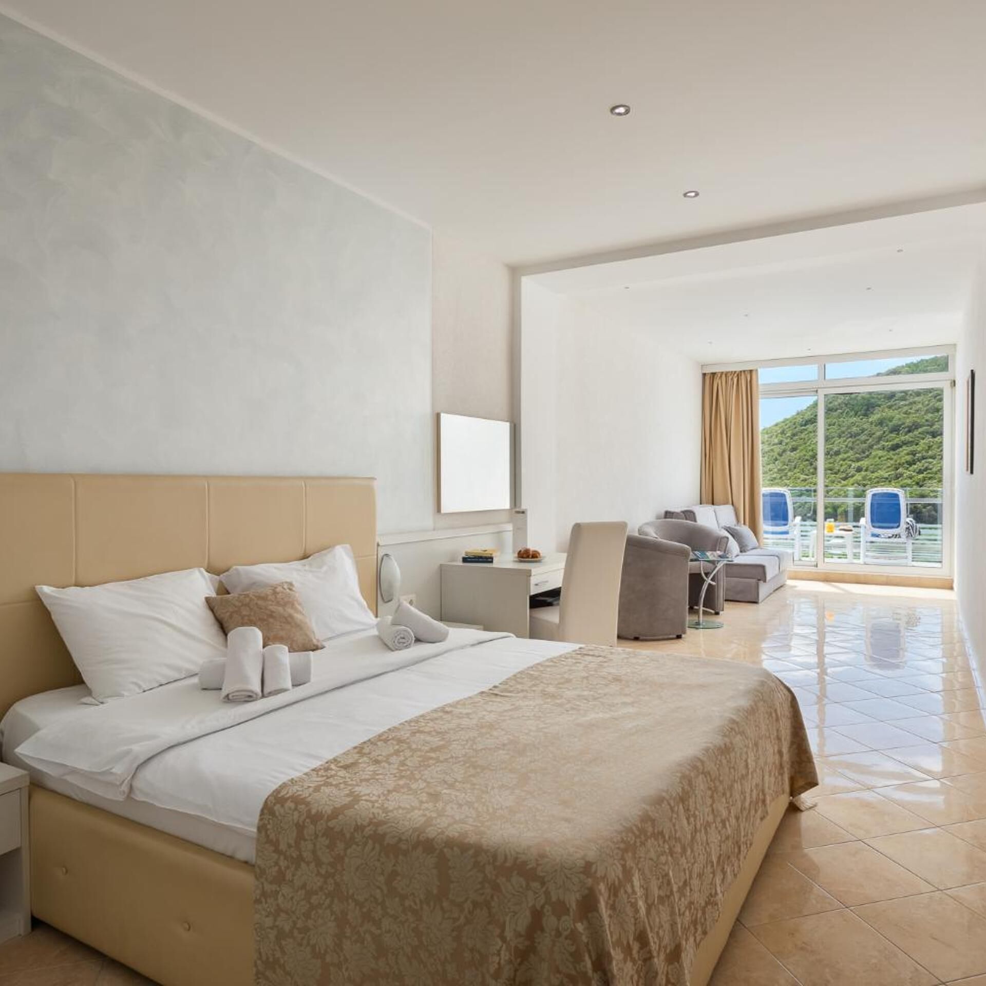 A hotel room with a bed, a desk, and a view of the outdoors.