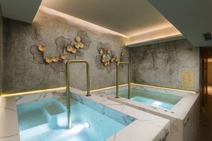A spa area with two hot tubs, marble flooring, and decorative wall art.