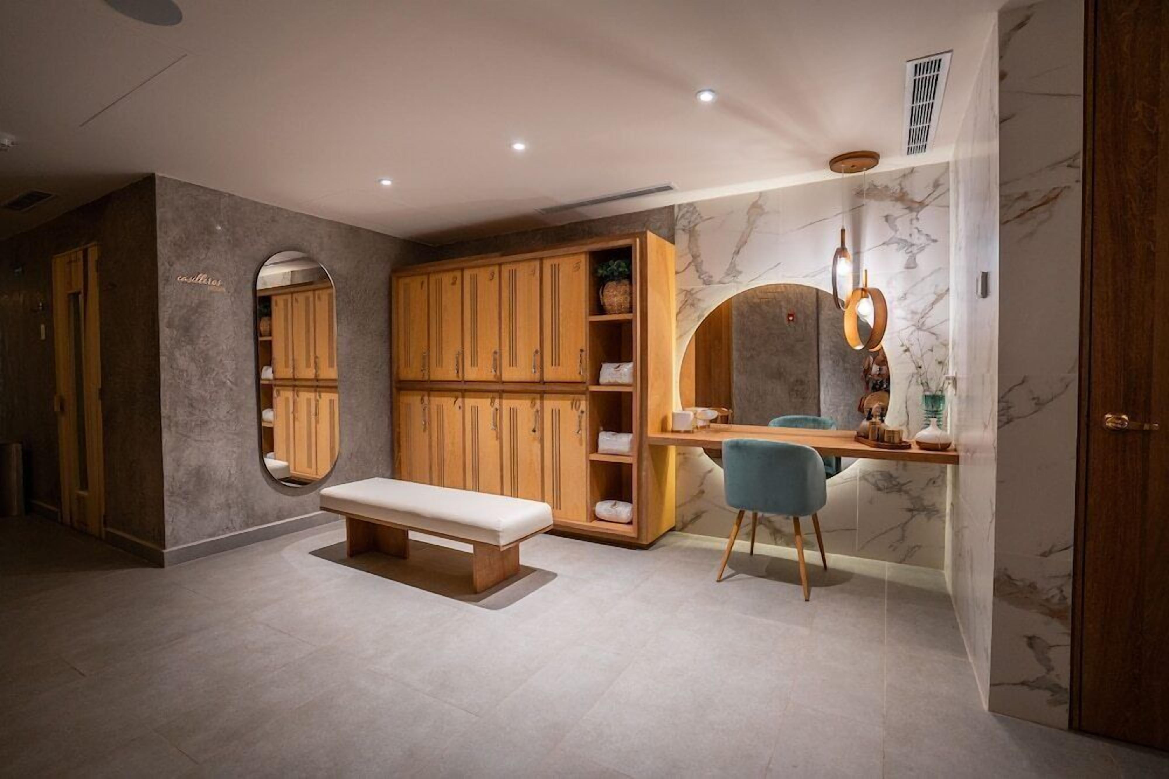 Una habitación con un banco de madera, un escritorio con una silla y un armario.