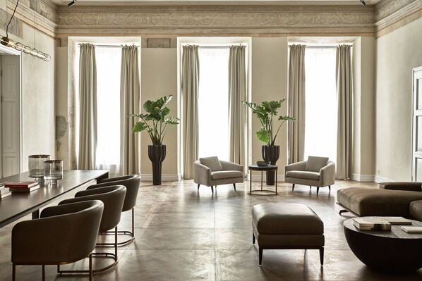 Un salón espacioso con piso de madera, un sofá, dos sillones, una mesa de centro y una zona de comedor con sillas y una mesa.