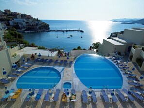 A resort with two swimming pools, sun loungers, and a view of the sea and buildings. - Bali Beach and Sofia Village (Mylopotamos)