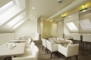 A modern dining area with high ceilings, skylights, and contemporary furniture. - Smart Hotel Schonbrunn (Vienna)