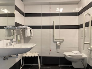 A bathroom with a white sink, a toilet, and a handrail. - Smart Hotel Schonbrunn (Vienna)