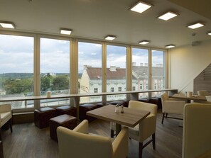 A modern hotel room with large windows, a wooden table, and comfortable seating. - Smart Hotel Schonbrunn (Vienna)