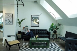 A loft-style room with a black leather sofa, a green coffee table, a checkered floor, and a skylight. - Smart Hotel Schonbrunn (Vienna)