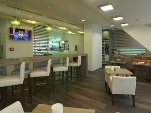 Un espace bar moderne comprenant un comptoir, des tabourets de bar et un écran de télévision.