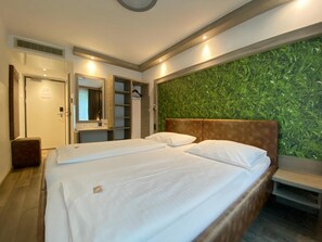 Une chambre d’hôtel avec un lit, une armoire, un miroir et un mur vert.