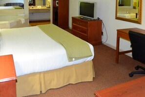 Ett hotellrum med en säng, ett skrivbord, en tv och en spegel.