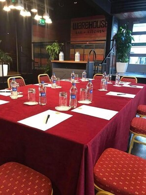 A conference room with a red table, white placemats, water bottles, and chairs. - Mcgettigans Hotel Letterkenny (Letterkenny)