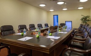 A conference room with a long table, chairs, water bottles, and a laptop.