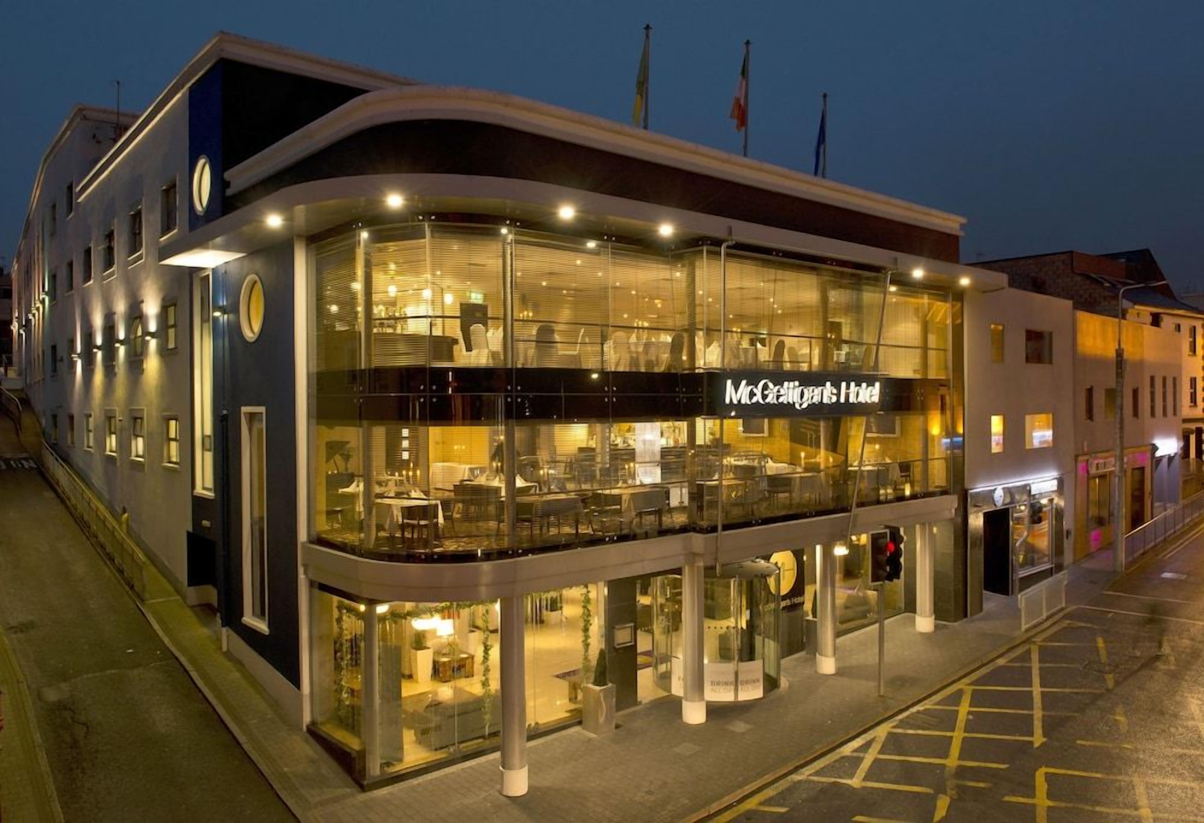 Un hotel moderno con fachada de vidrio, un letrero llamativo y un área de balcón.