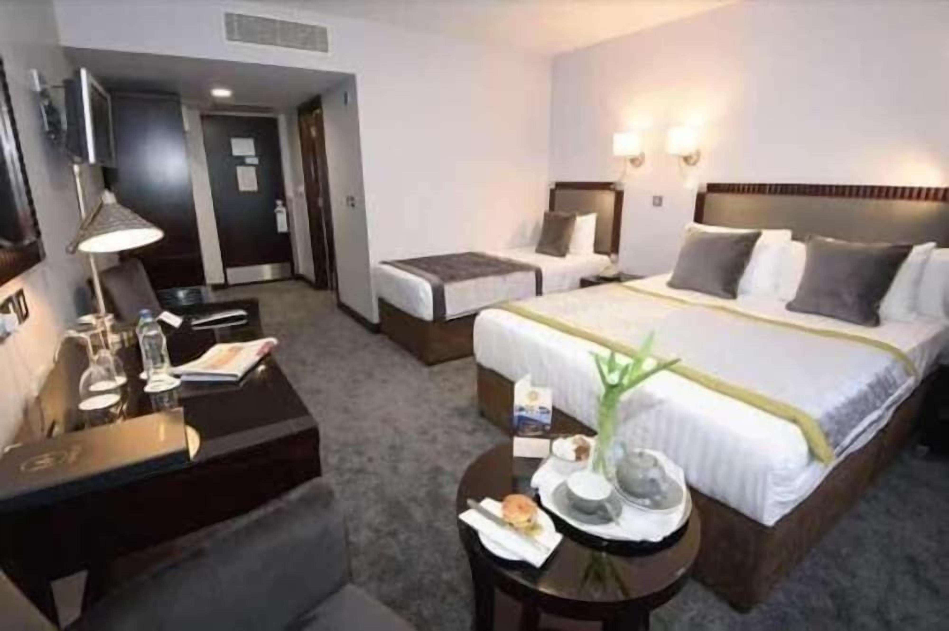 A hotel room with a bed, bedside tables, a desk, and a chair.