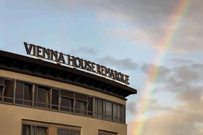 A building with the sign 'VIENNA HOUSE REMARQUE' and a rainbow in the sky. - Vienna House by Wyndham Remarque Osnabruck (Osnabrueck)