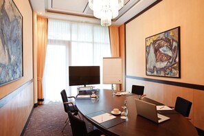 A conference room with a large table, chairs, a laptop, a TV, and artwork on the wall. - Vienna House by Wyndham Remarque Osnabruck (Osnabrueck)