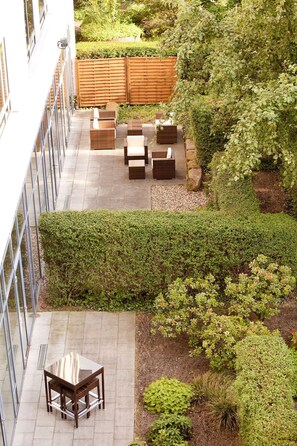 A rooftop patio with outdoor furniture, a wooden fence, and various plants. - Vienna House by Wyndham Remarque Osnabruck (Osnabrueck)
