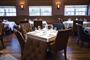 Ein Restaurantinnenraum mit Sitzecken und Tischen, Holzböden und Fenstern mit Blick.