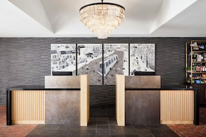 Un mostrador de recepción de diseño moderno, un candelabro y un cuadro abstracto grande en la pared.