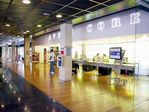 A spacious indoor area with a long counter, possibly a reception or service desk, and a large illuminated sign above. - Select Hotel Apple Park Maastricht (Maastricht)