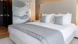 Une chambre moderne avec un grand lit, une tête de lit et une œuvre d’art accrochée au mur.