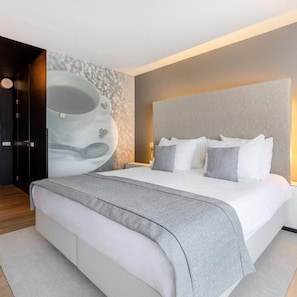 Une chambre moderne avec un grand lit, une tête de lit et une œuvre d’art accrochée au mur.