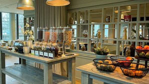 Un espace buffet pour le petit-déjeuner où divers aliments et accompagnements sont présentés dans des bocaux et des paniers.