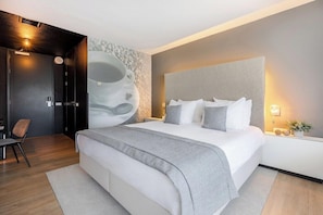 A modern hotel room with a large bed, a seating area, and a wall-mounted artwork. - Select Hotel Apple Park Maastricht (Maastricht)