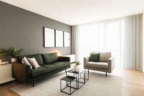 A modern living room with a green sofa, a beige armchair, a coffee table, and a large window with curtains. - Select Hotel Apple Park Maastricht (Maastricht)